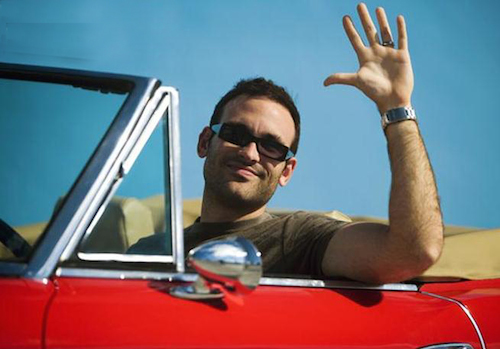 close-up_of_a_mid_adult_man_sitting_in_a_convertible_car_waving_his_hand_miami_florida_usa_gwj82773437